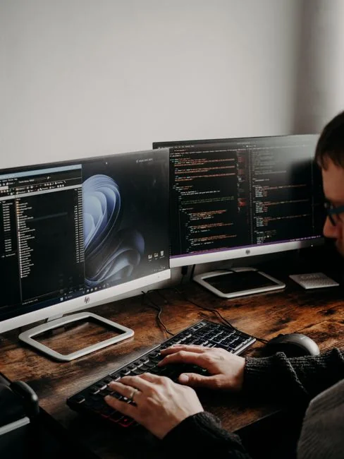Dual monitors on a desk, showcasing web design in a modern office setting.
