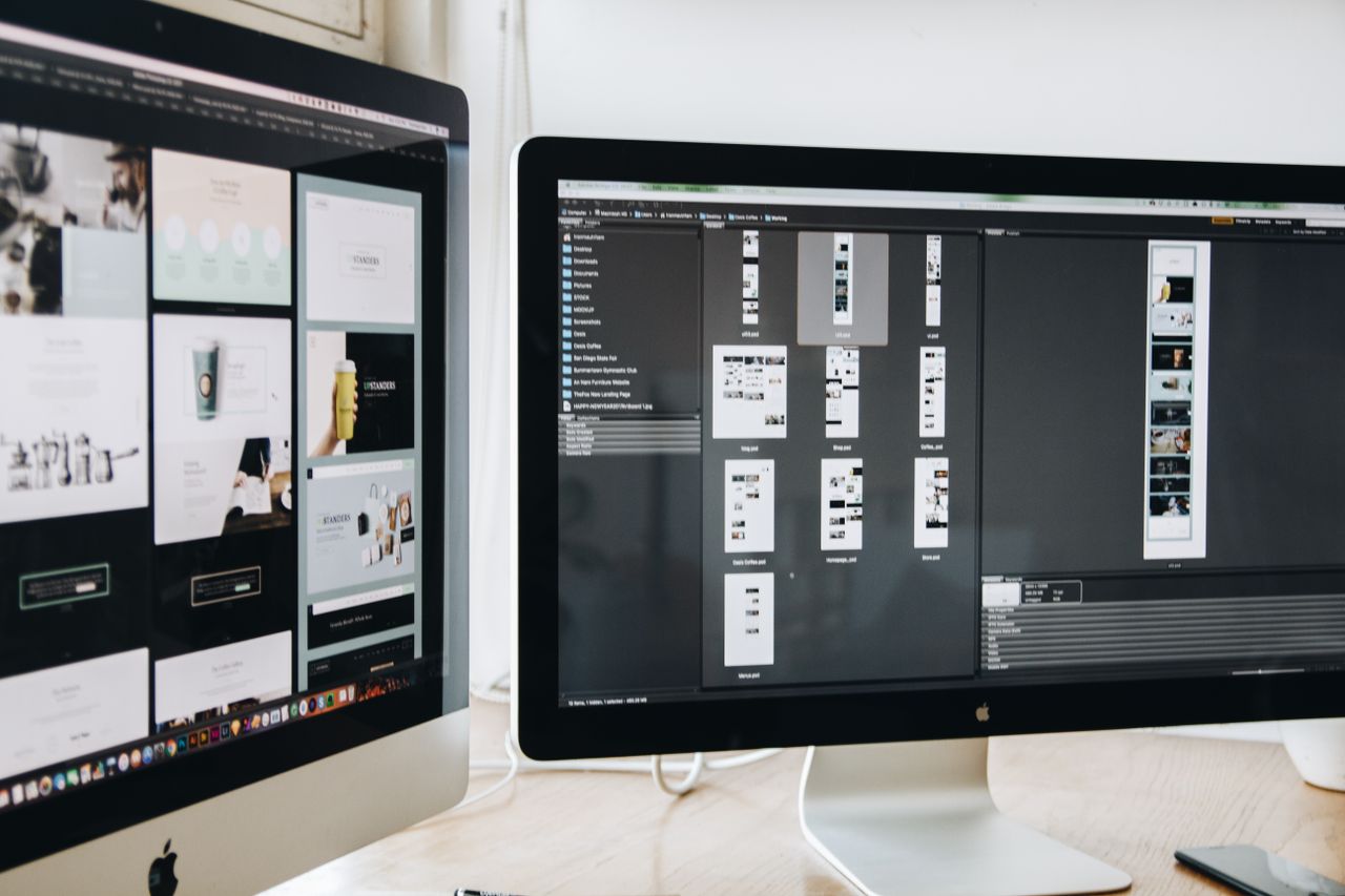 Un ambiente di lavoro moderno con due monitor per computer che mostrano progetti di web design, a sottolineare tecnologia e produttività.